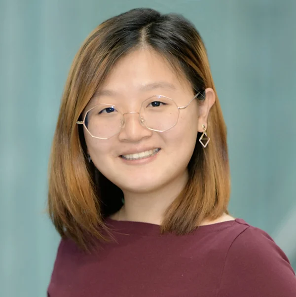 An Asian woman in a dark red shirt, wearing glasses