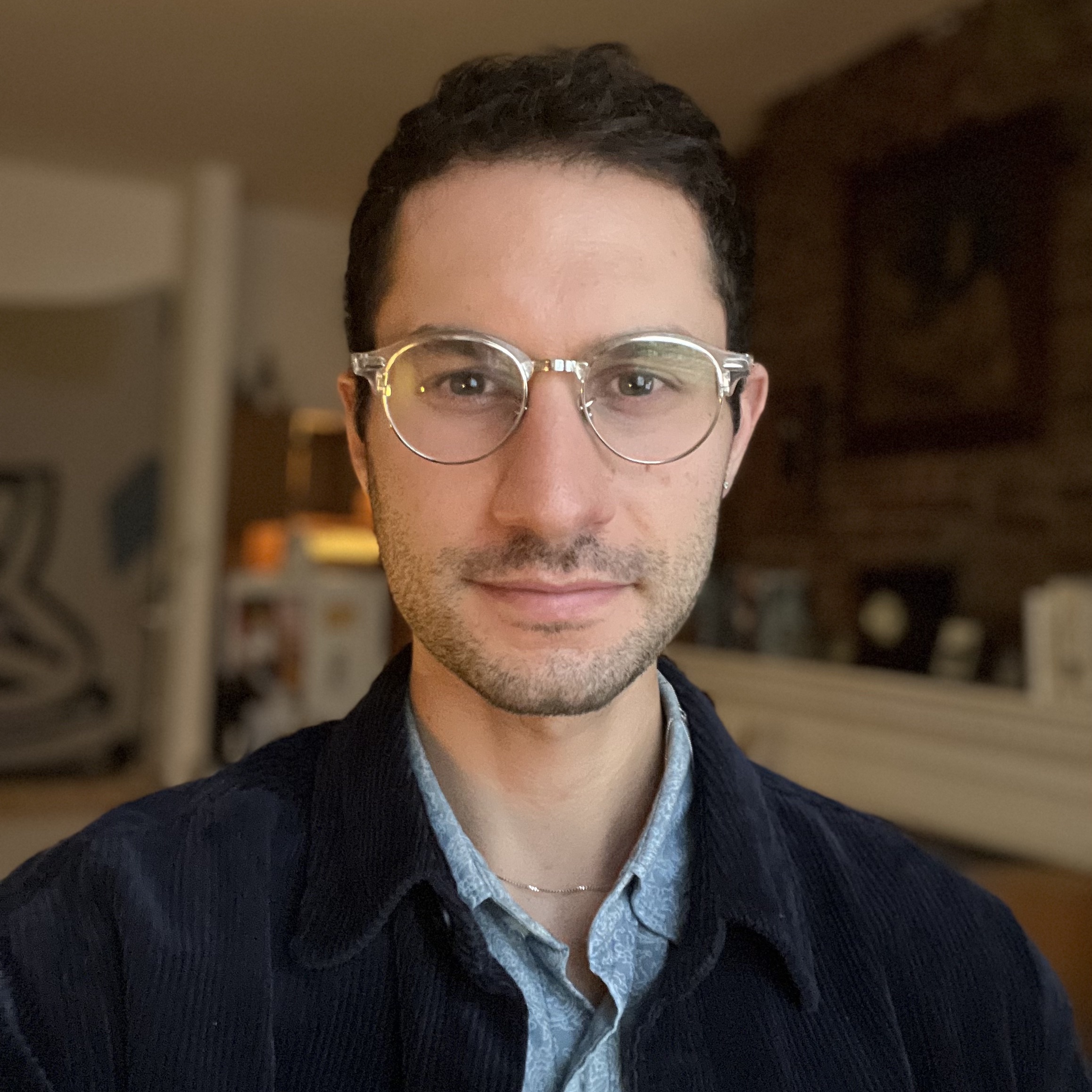 Skinny Jewish dude with short curly hair and transparent, silver glasses.