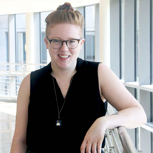 Headshot of Erin Brady, a redheaded woman in glasses and a black top 